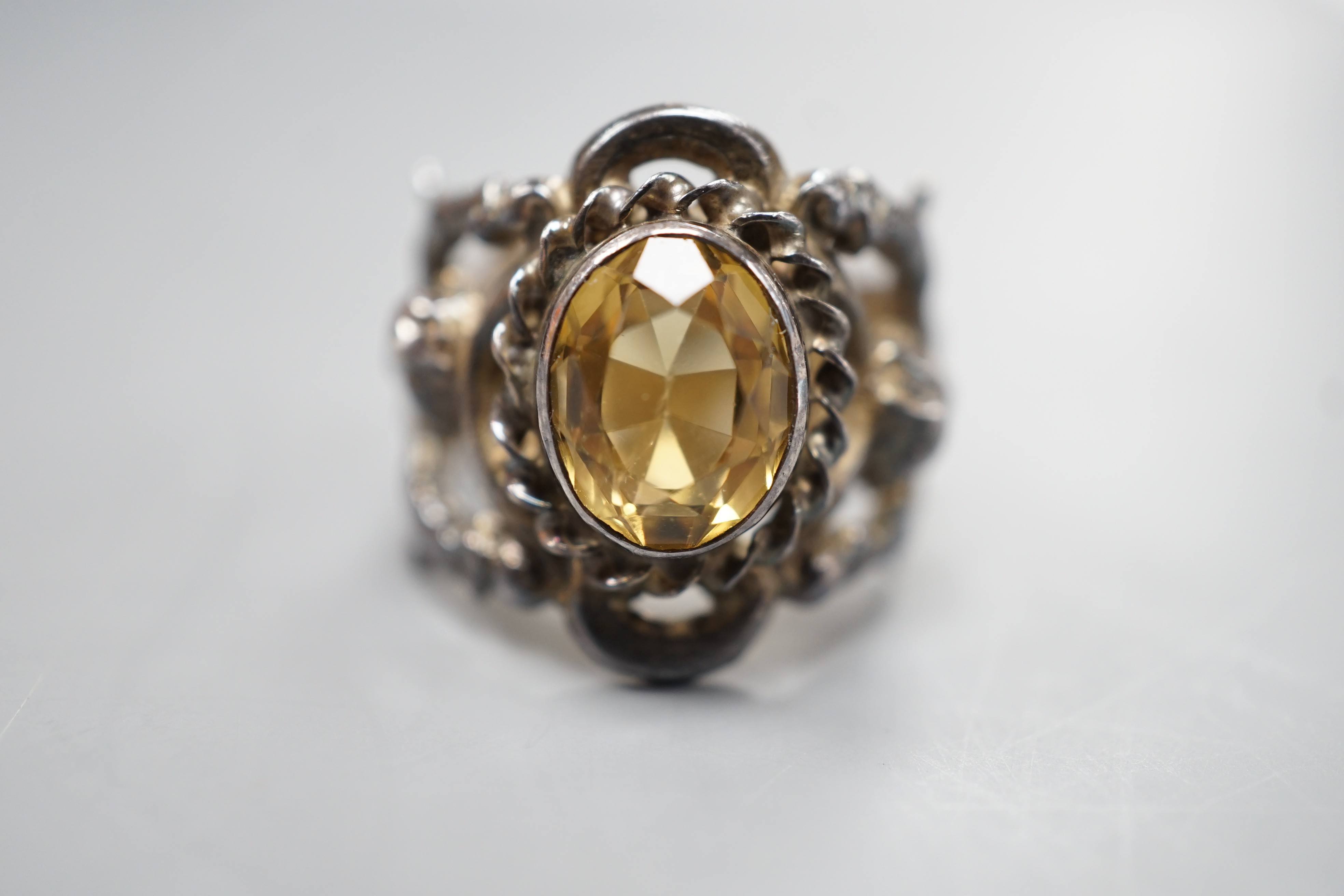 A 1960's silver and oval cut citrine set ring, the shank modelled and twin cupids, size O, gross weight 9.2 grams.